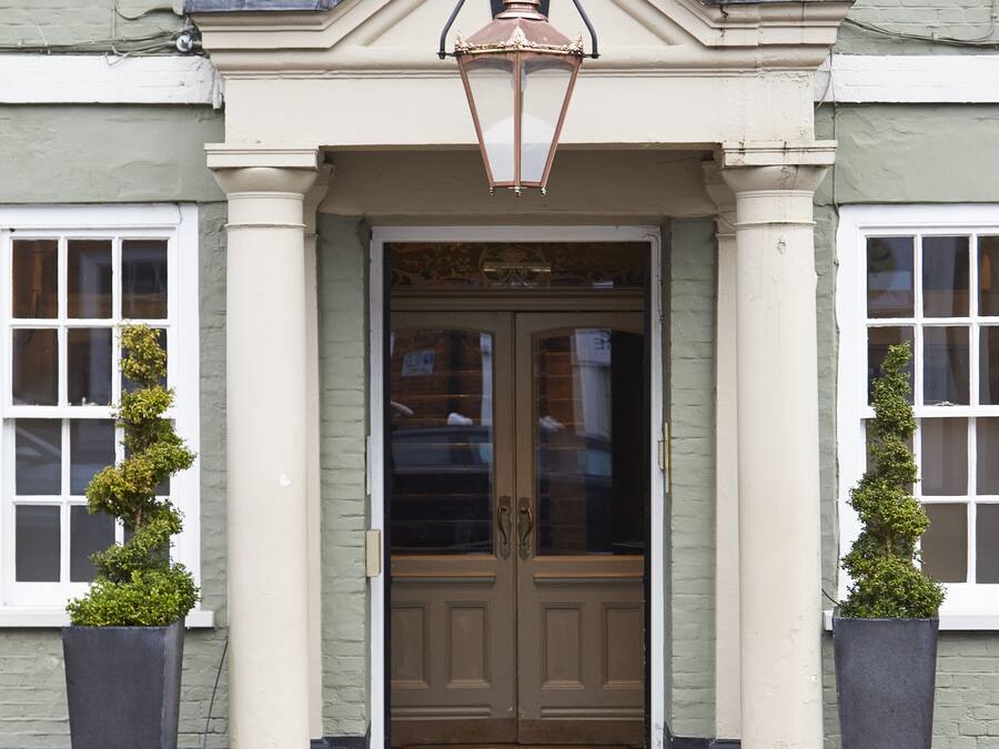 A building with a double door entrance, two potted plants on either side, and a decorative lantern above the door.