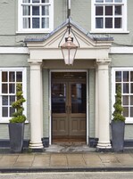 A building with a double door entrance, two potted plants on either side, and a decorative lantern above the door.