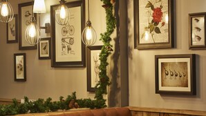 A cozy seating area with a brown leather couch, framed artwork on the walls, and decorative lights. - Swan Hotel by Greene King Inns (Alton)