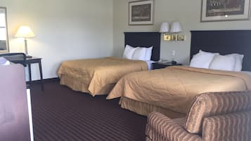 Habitación de hotel con dos camas, un escritorio, una silla y dos lámparas.