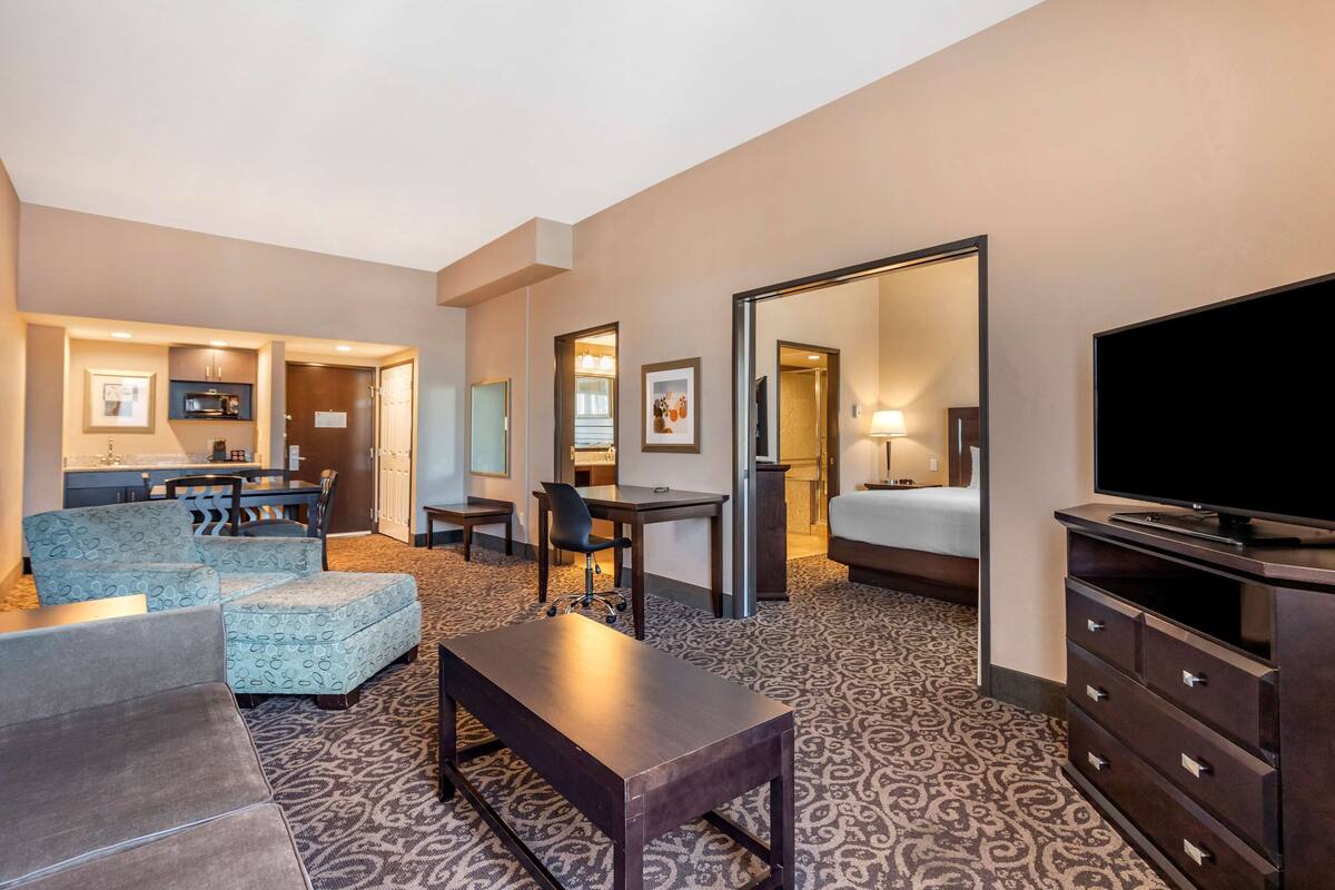 Ein Hotelzimmer mit Sofa, Schreibtisch, Fernseher, Bett und Bad.