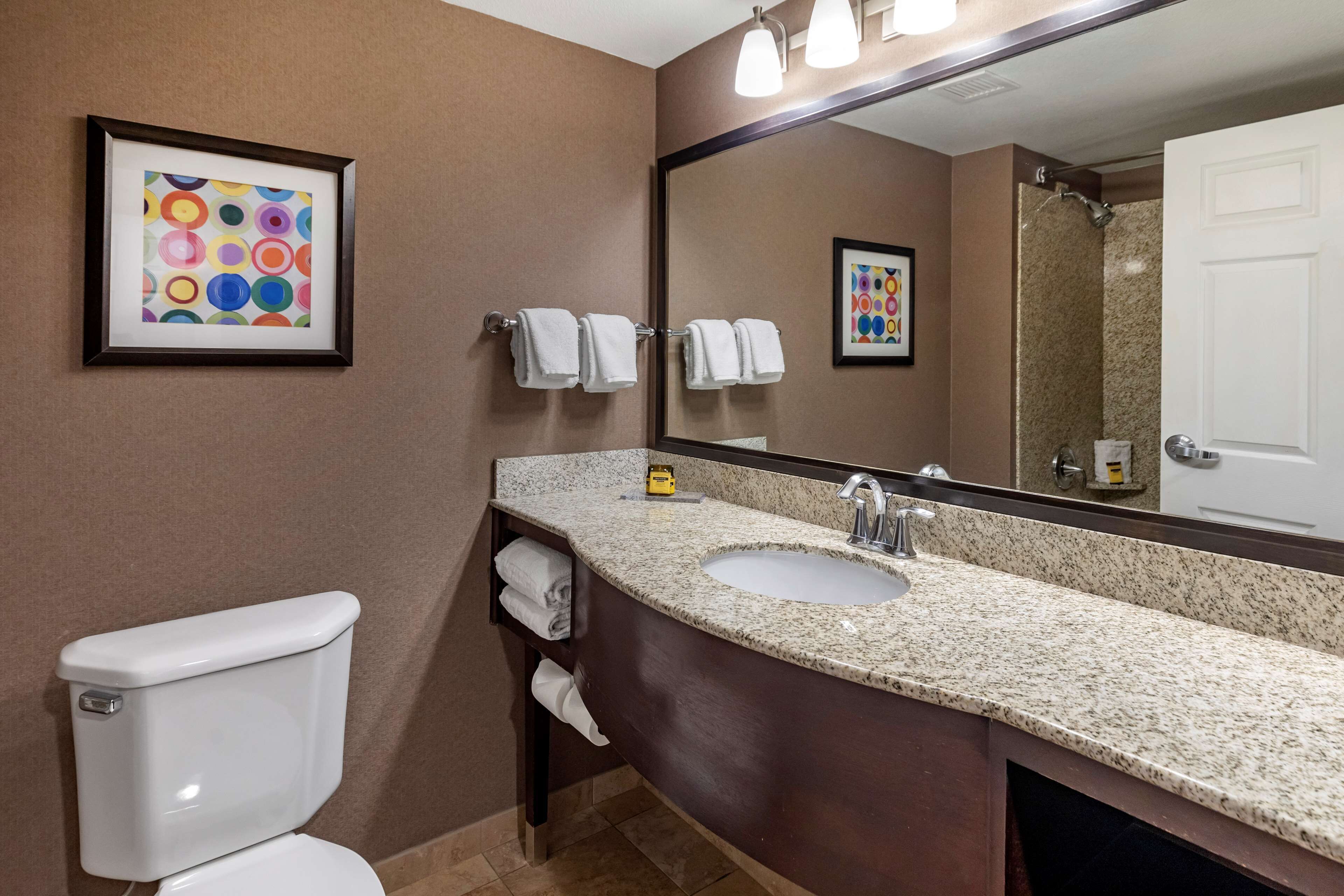 A bathroom with a toilet, sink, mirror, and towel rack.