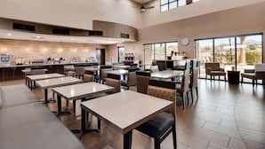 Un restaurante moderno con techos altos, amplias ventanas y diversas opciones de asientos, incluyendo mesas y cabinas.