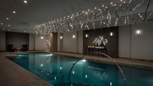 A swimming pool with a modern design, surrounded by a lounge area with seating and a decorative wall with flowers.
