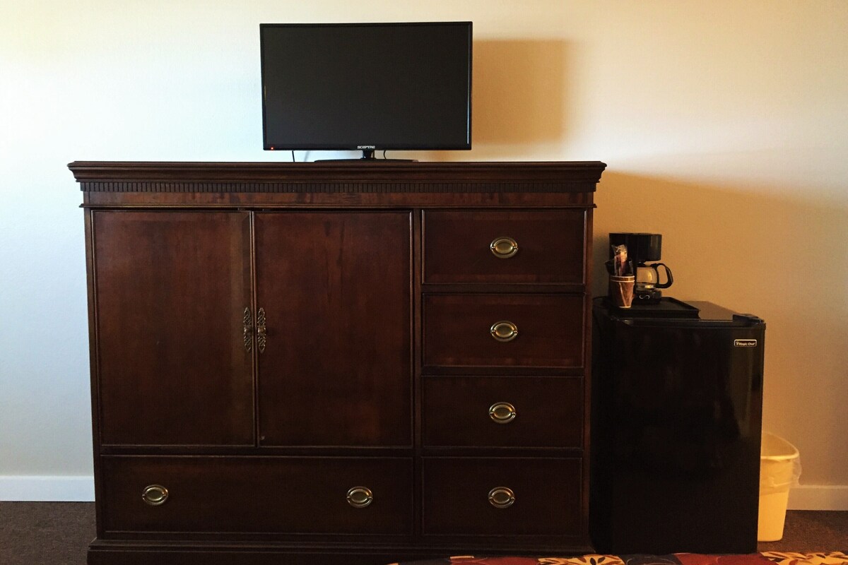 Een donkere houten dressoir met lades en een flatscreen televisie erboven.