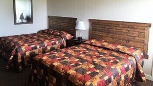 Quarto de hotel com duas camas, cada uma com cabeceira de madeira, mesa de cabeceira e abajur.