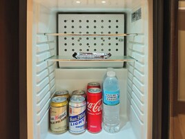 Geladeira com prateleira, duas latas de cerveja, uma garrafa de água e uma barra de chocolate.