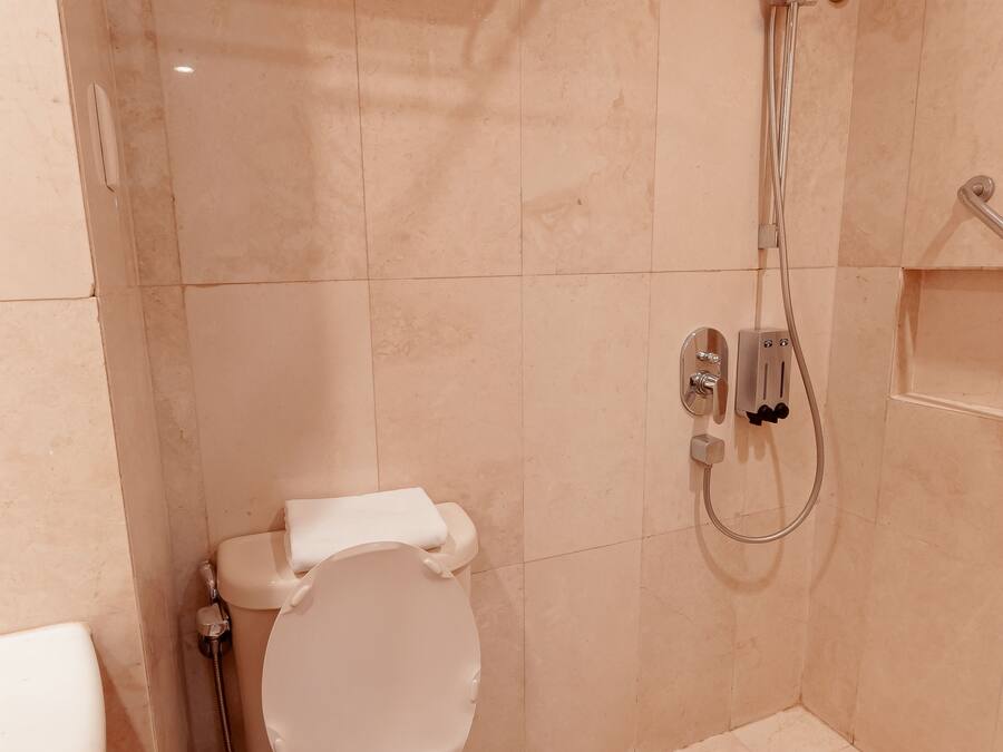 A small bathroom with a toilet, a shower, and a towel rack.