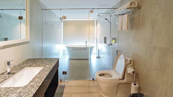 Un baño moderno con encimera de granito, inodoro, ducha y lavabo.