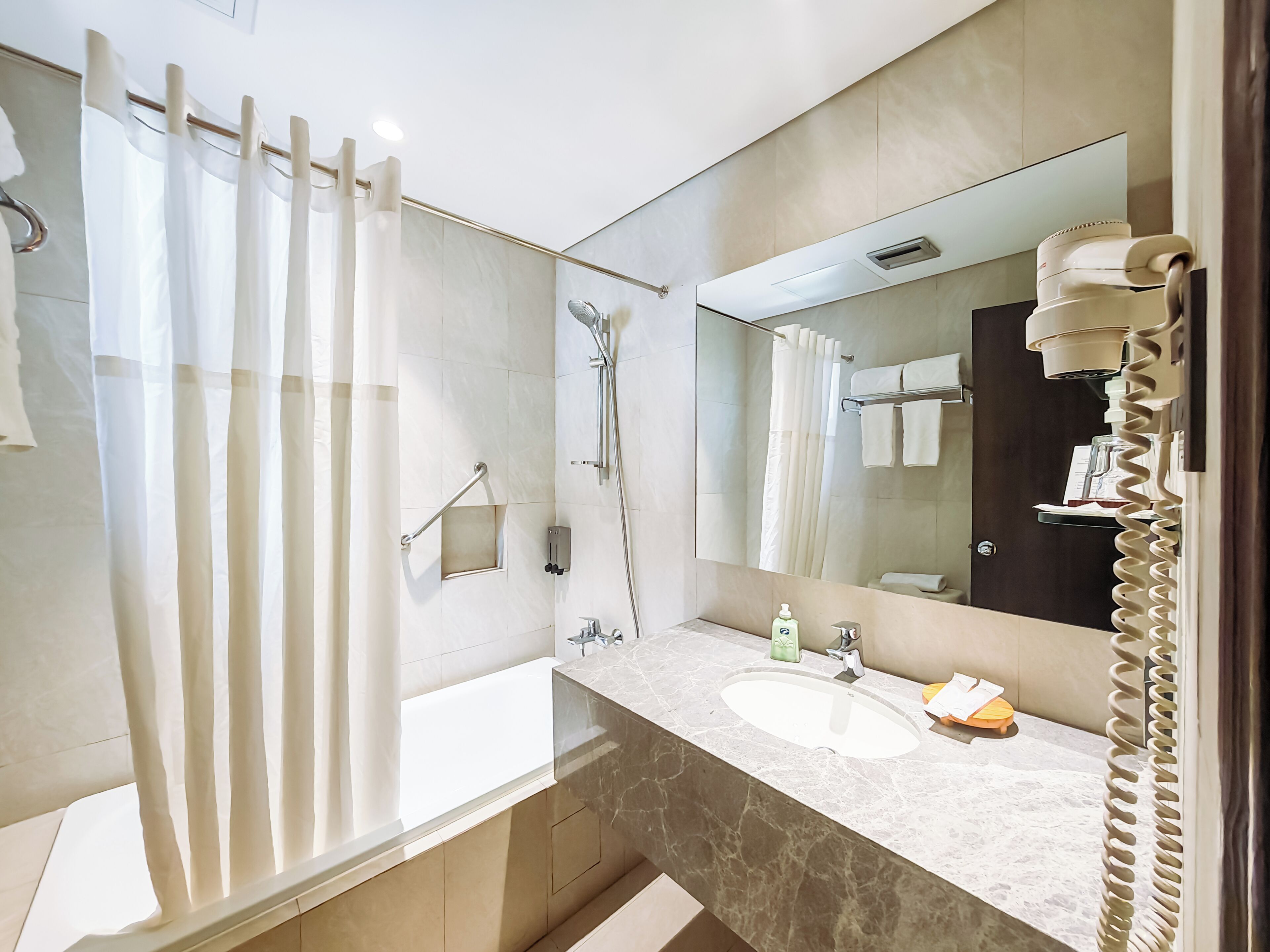 A modern bathroom with a bathtub, a shower, a sink, and a large mirror.