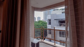 A balcony with a view of city buildings and greenery. - City Garden Suites Manila (Manila)