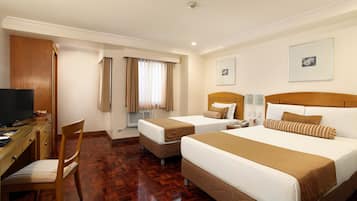 A hotel room with two beds, a desk with a computer, a chair, and a television.