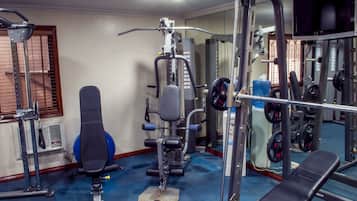 A gym with exercise equipment, a bench, and a mirrored wall.