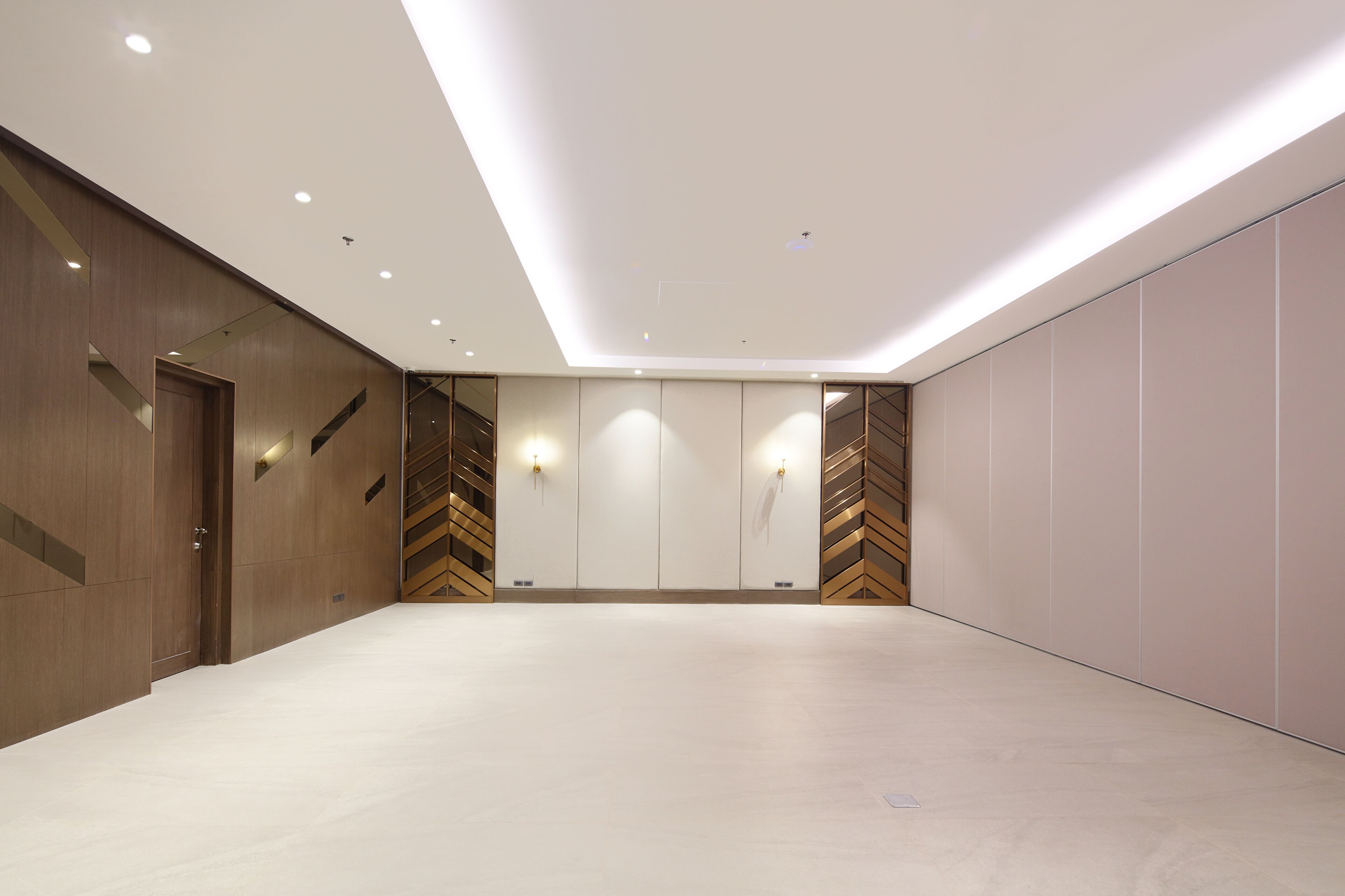 A spacious room with a high ceiling, recessed lighting, and a neutral color palette.