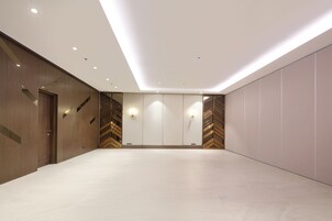 A spacious room with a high ceiling, recessed lighting, and a neutral color palette.