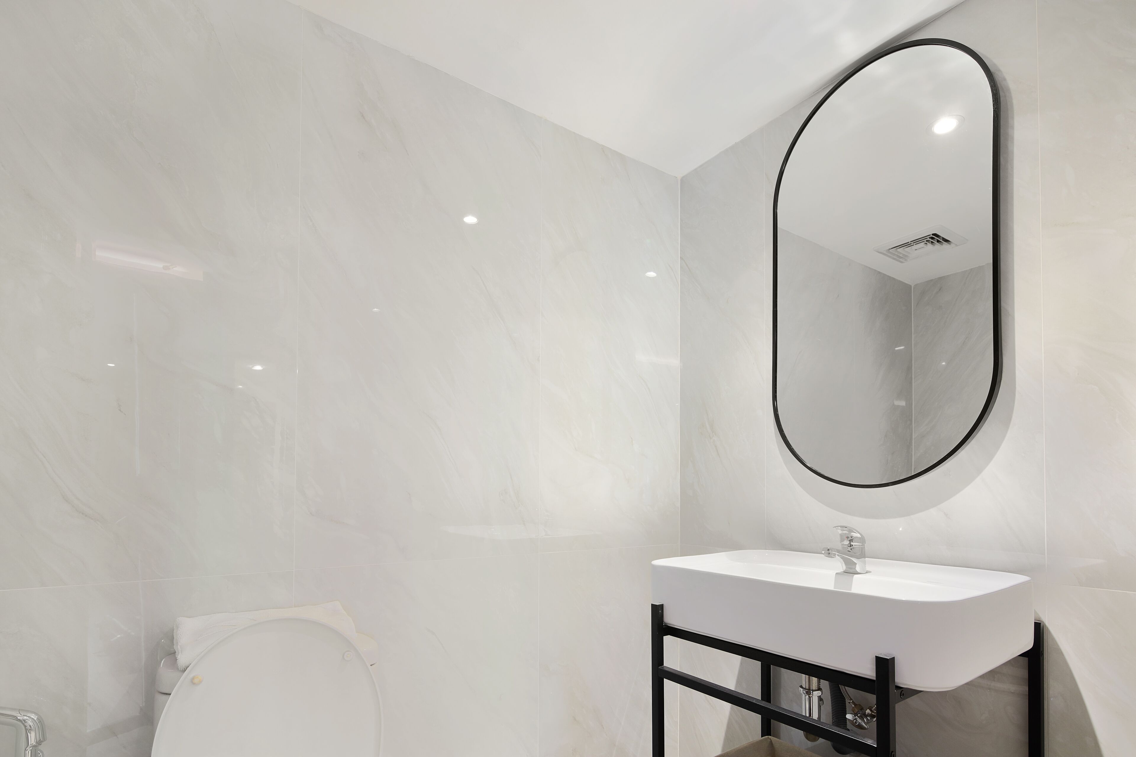 A modern bathroom with a white sink, black frame, and a large mirror.