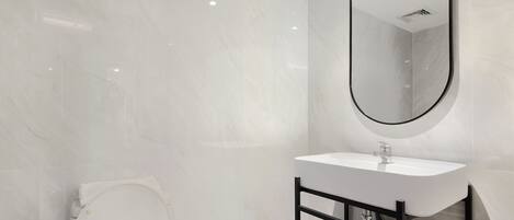 A modern bathroom with a white sink, black frame, and a large mirror.
