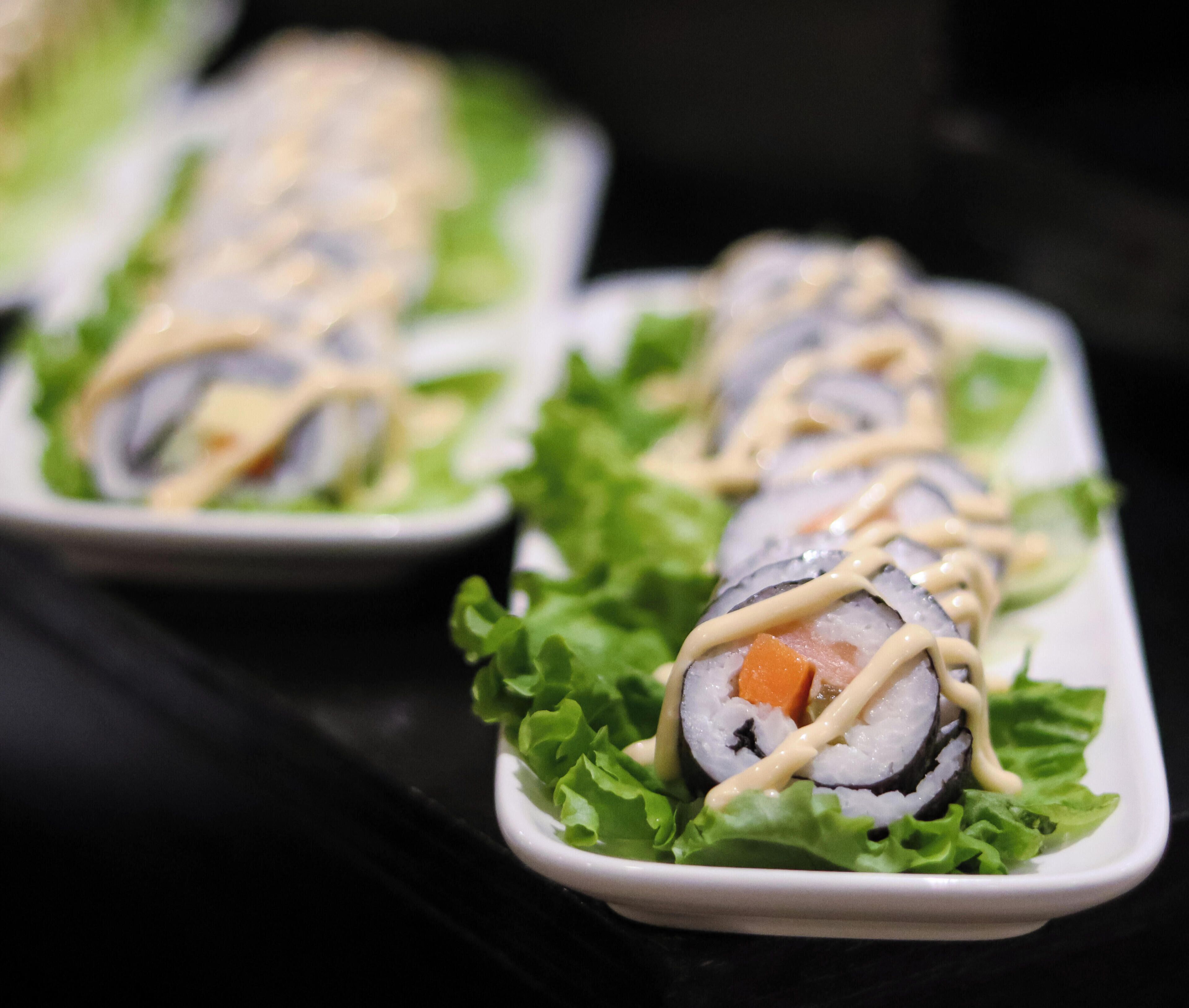 Sushi rolls on a bed of lettuce leaves, arranged on a white plate.