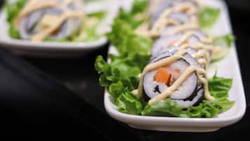Sushi rolls on a bed of lettuce leaves, arranged on a white plate.