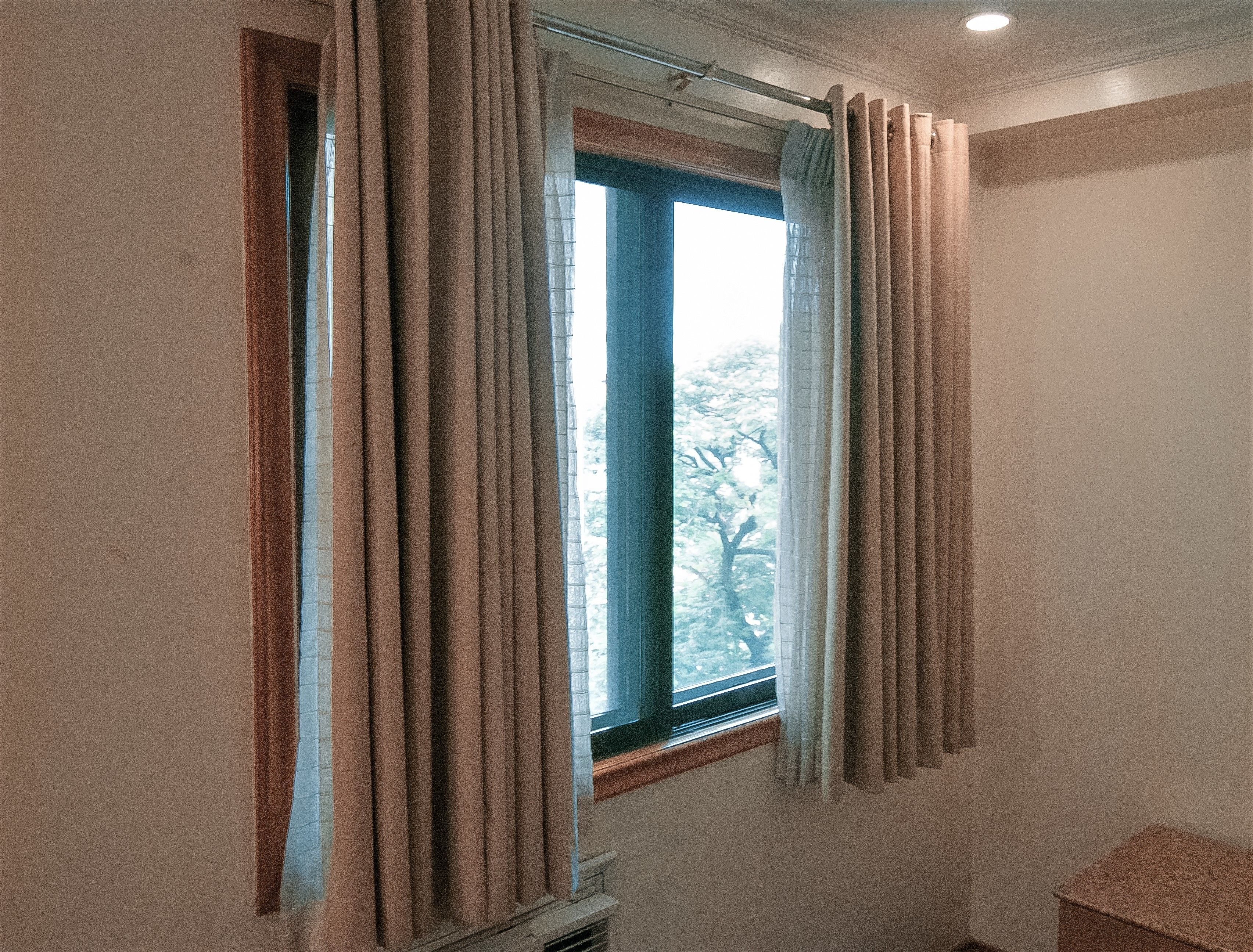 Una habitación con ventana, cortinas y radiador.