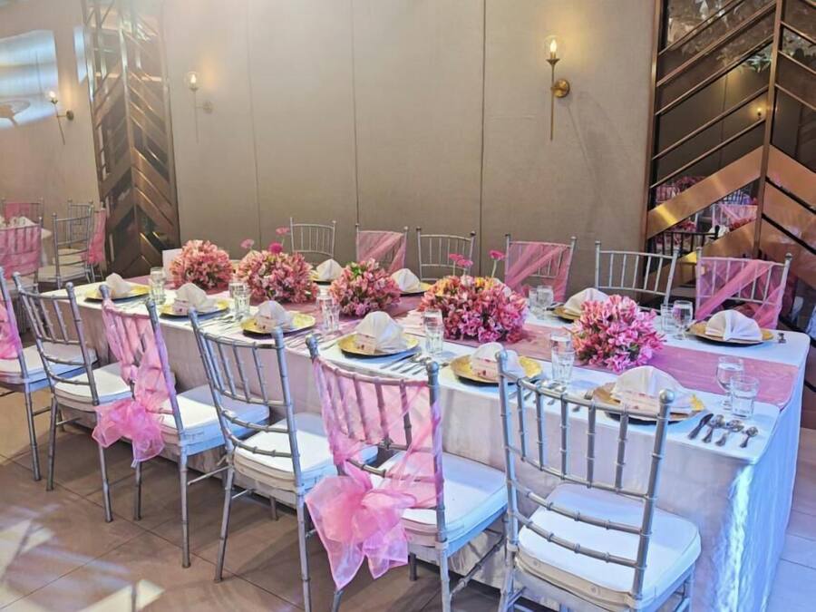 Un salón de banquetes con mesas redondas, sillas y centros de mesa florales.