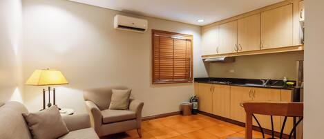Un espacio habitable compacto con kitchenette, un sofá, una silla y una lámpara.