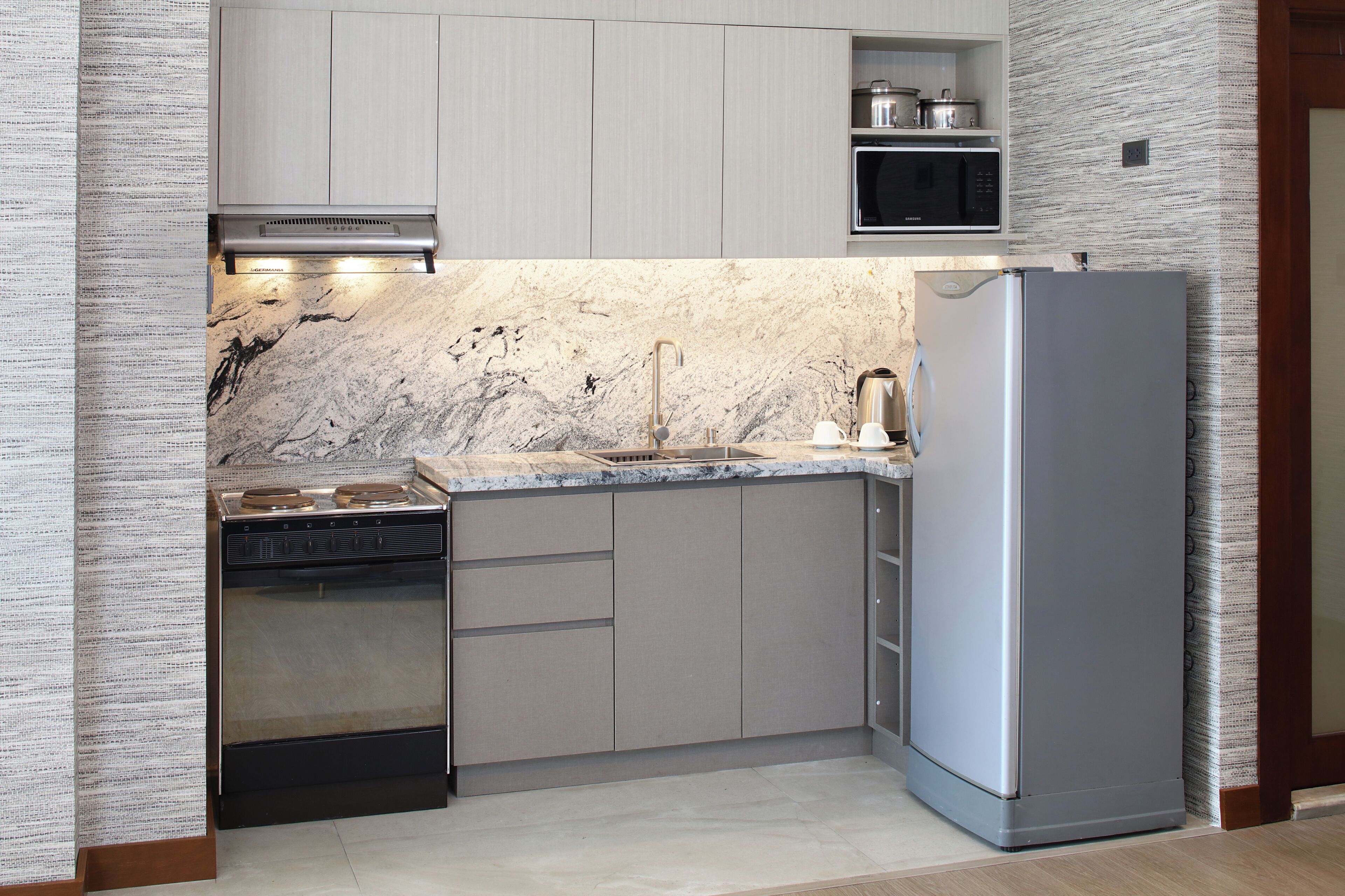 Uma cozinha moderna com forno embutido, geladeira de aço inoxidável e bancada de mármore.