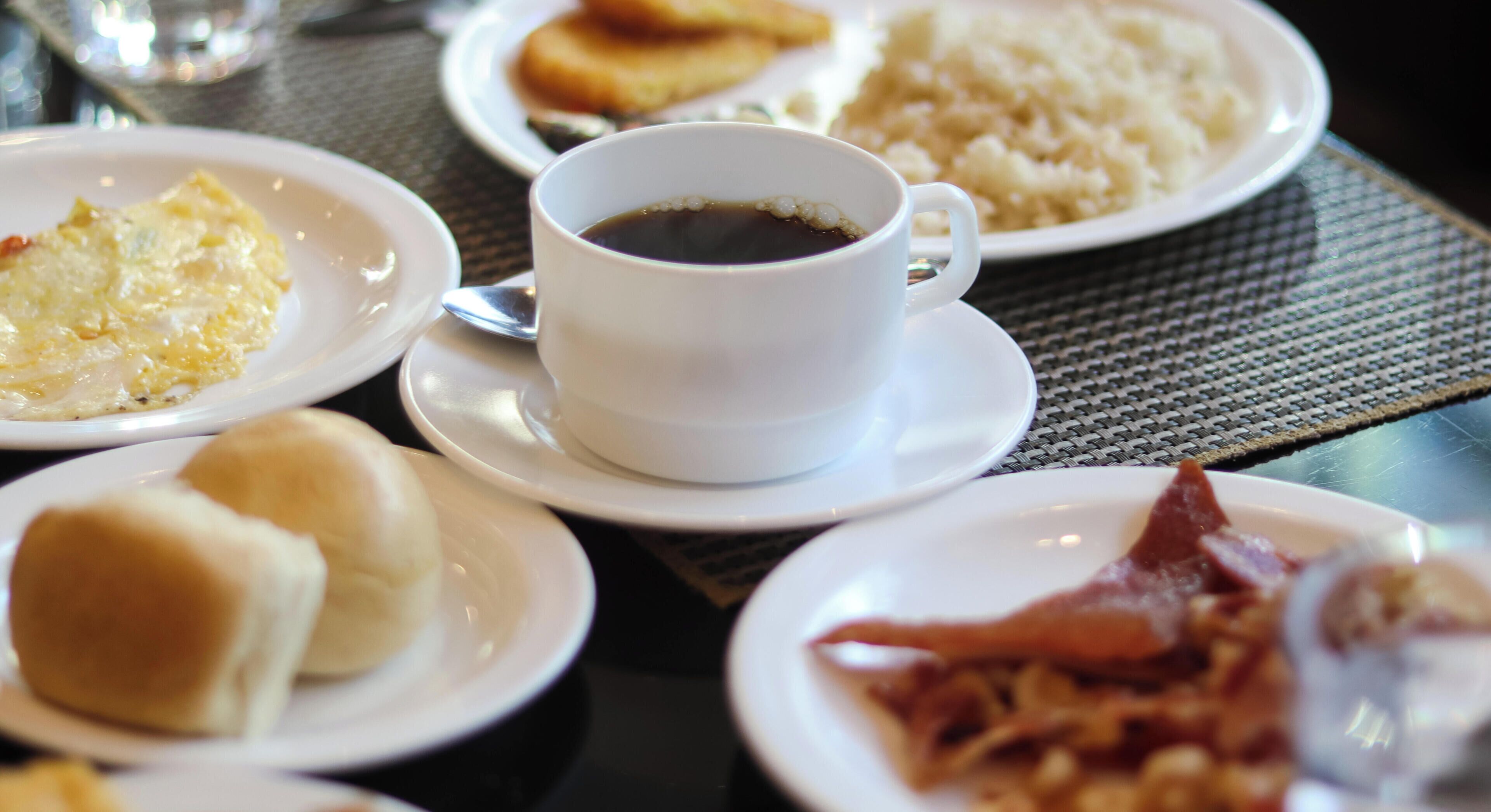 A table with various breakfast items including eggs, bacon, and coffee.