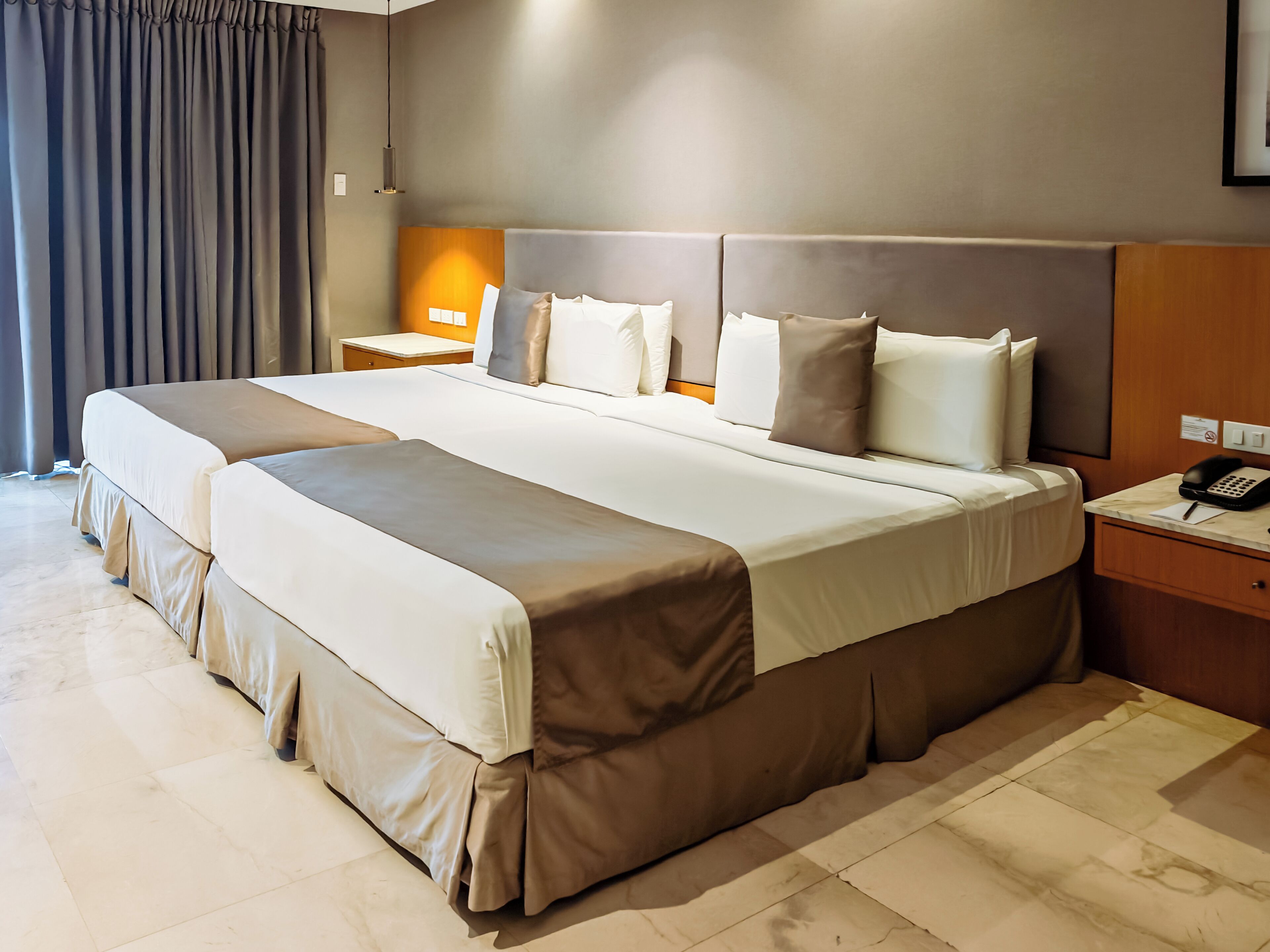 A large bed with a headboard, a bedside table with a lamp, and a phone on the nightstand.