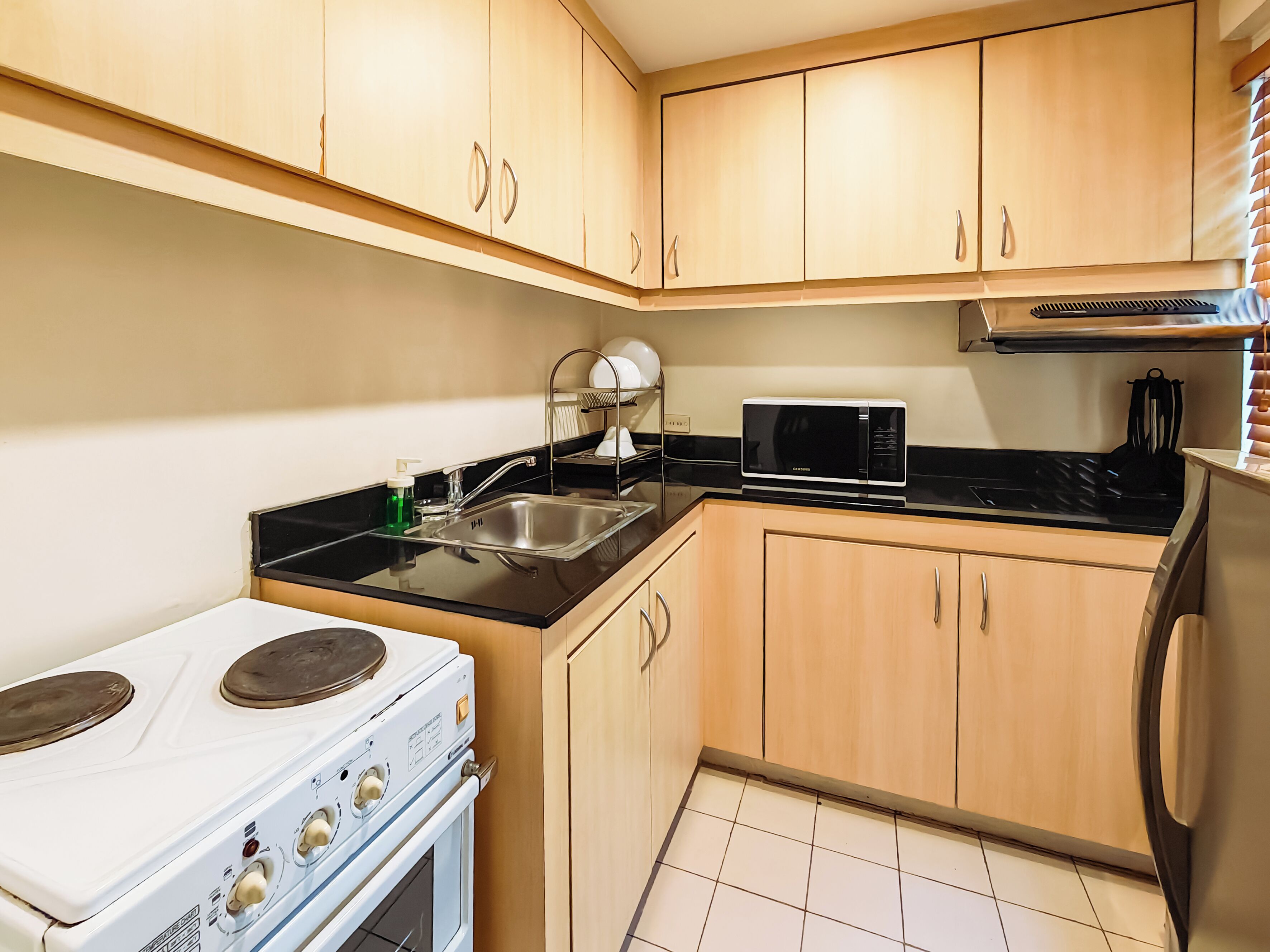 A compact kitchen with a stove, sink, microwave, and wooden cabinets.