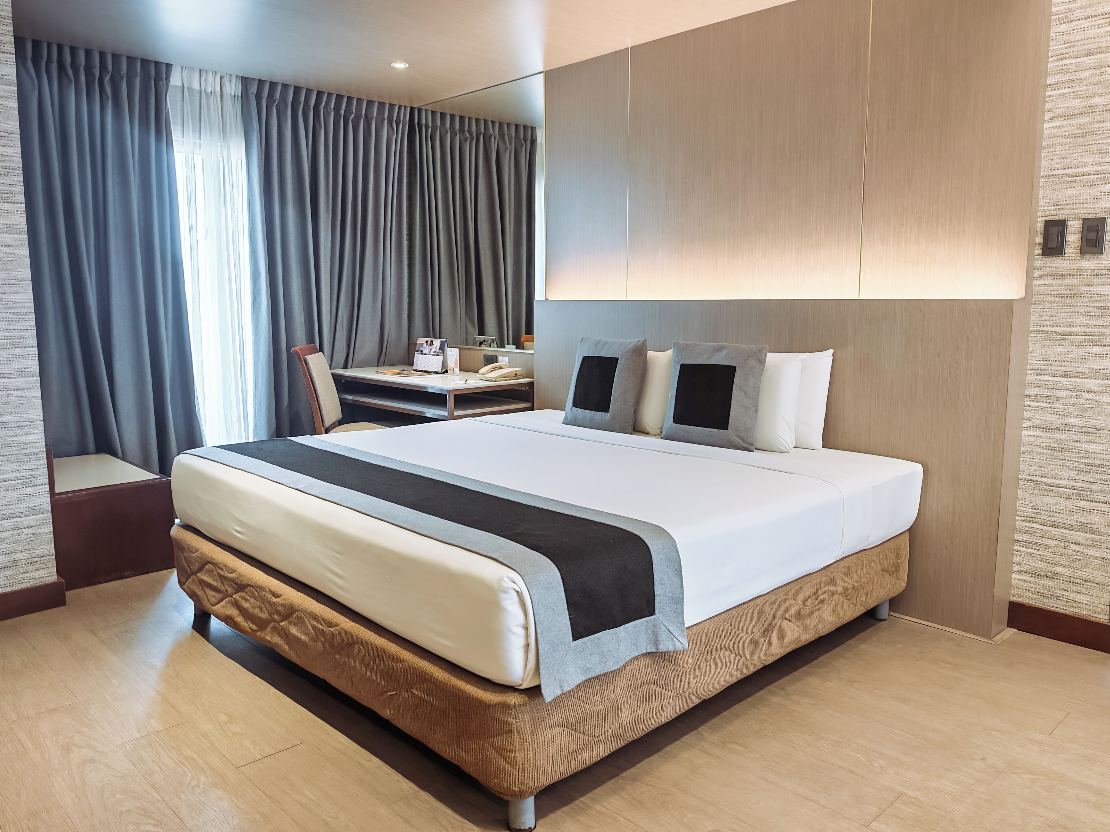 Habitación de hotel moderna con una cama grande, un escritorio con silla y vistas a la ciudad desde la ventana.