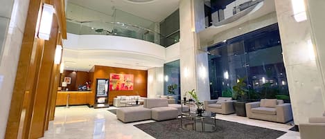 A spacious lobby with a reception desk, seating area, and large windows.