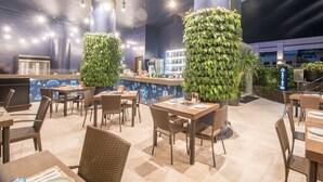 Un comedor interior con mesas y sillas, una barra y plantas decorativas.