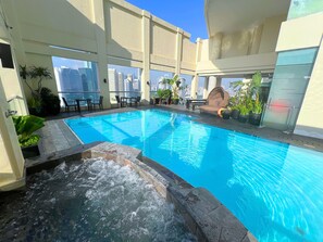 A rooftop pool with clear blue water, surrounded by potted plants and outdoor furniture. - City Garden Hotel Makati (Makati)