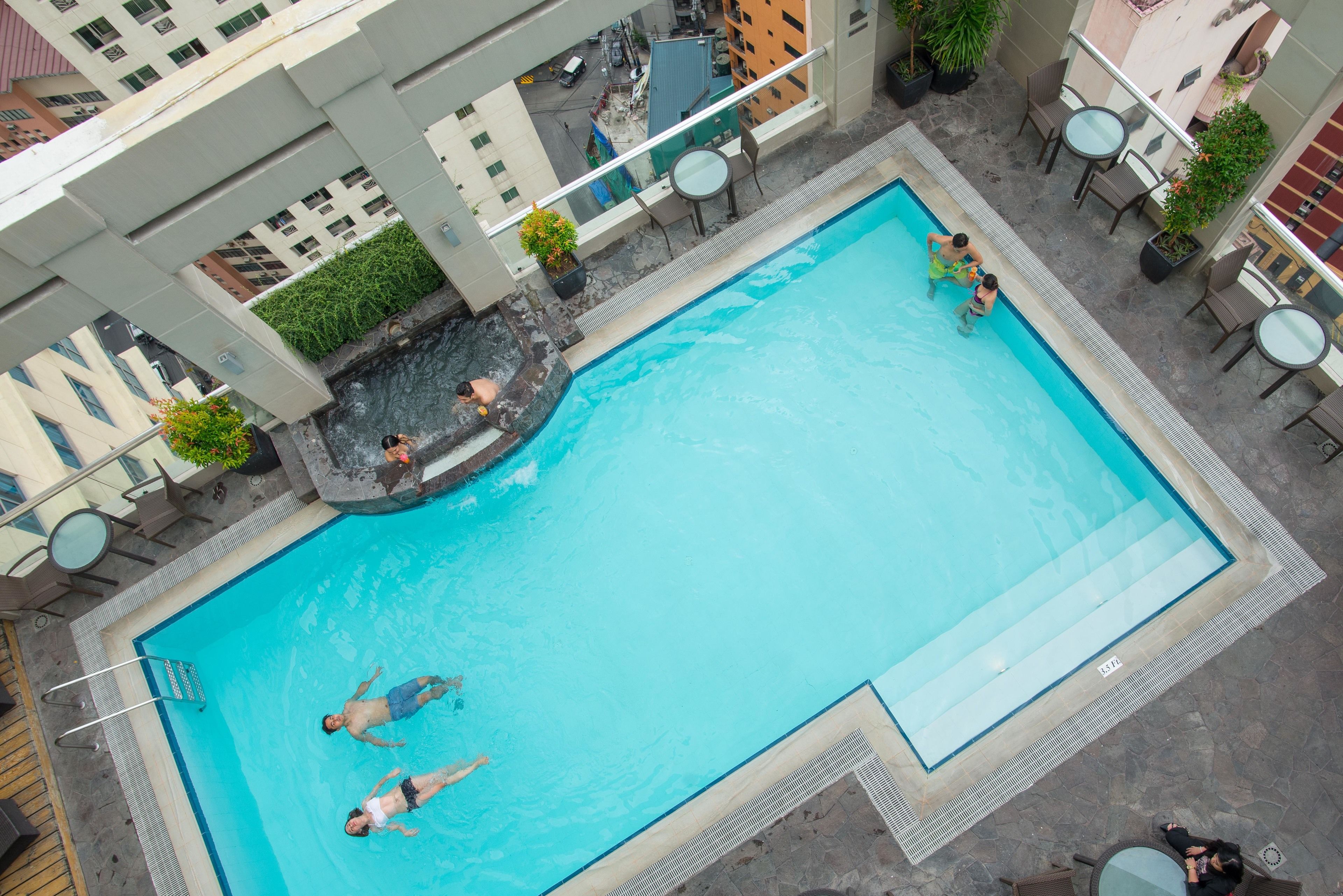 An outdoor swimming pool with a few people swimming and relaxing.