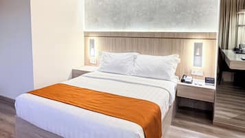A modern hotel room with a large bed, wooden headboard, bedside tables with lamps, and a mirror.