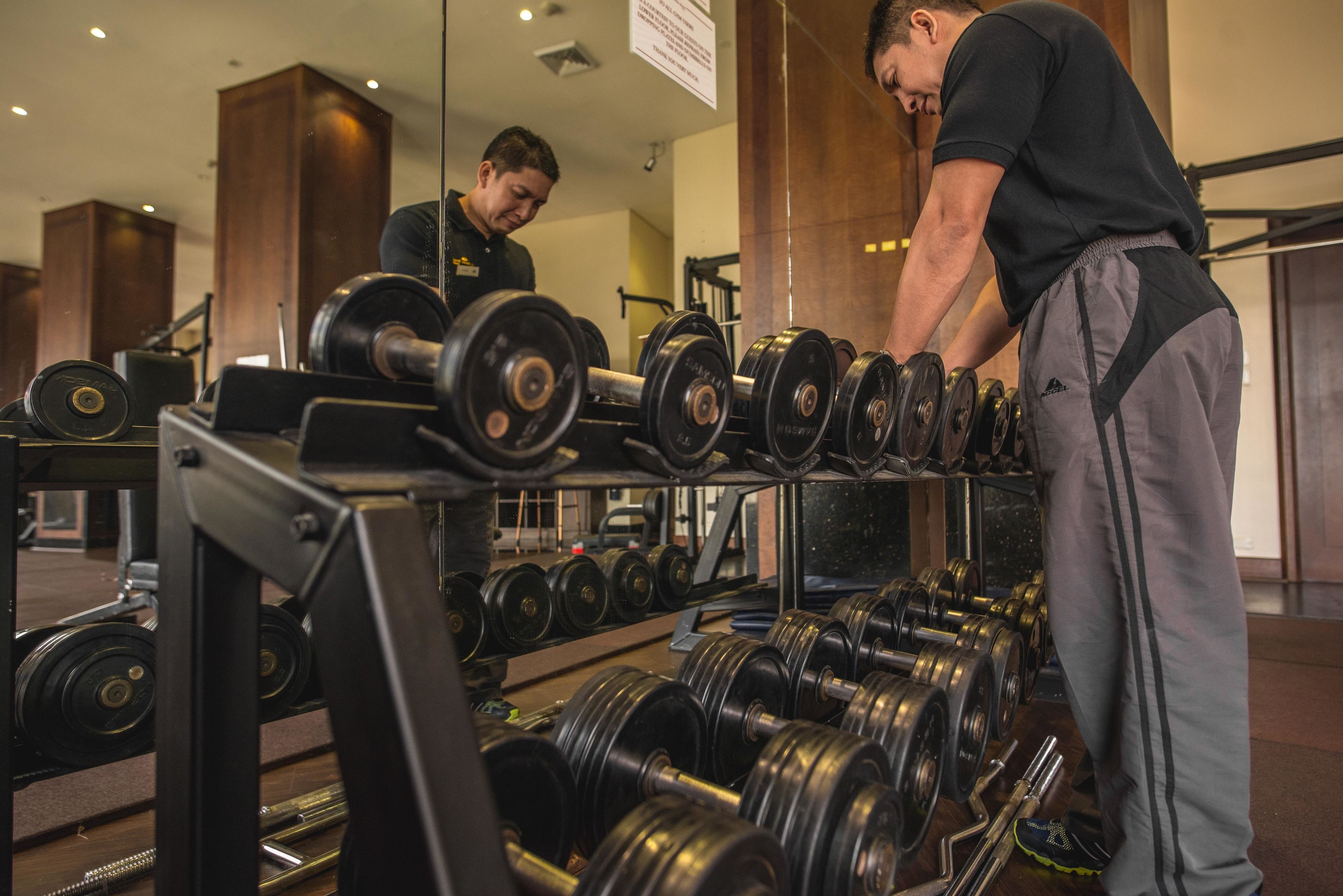 A gym with weightlifting equipment and a mirror reflecting the interior.