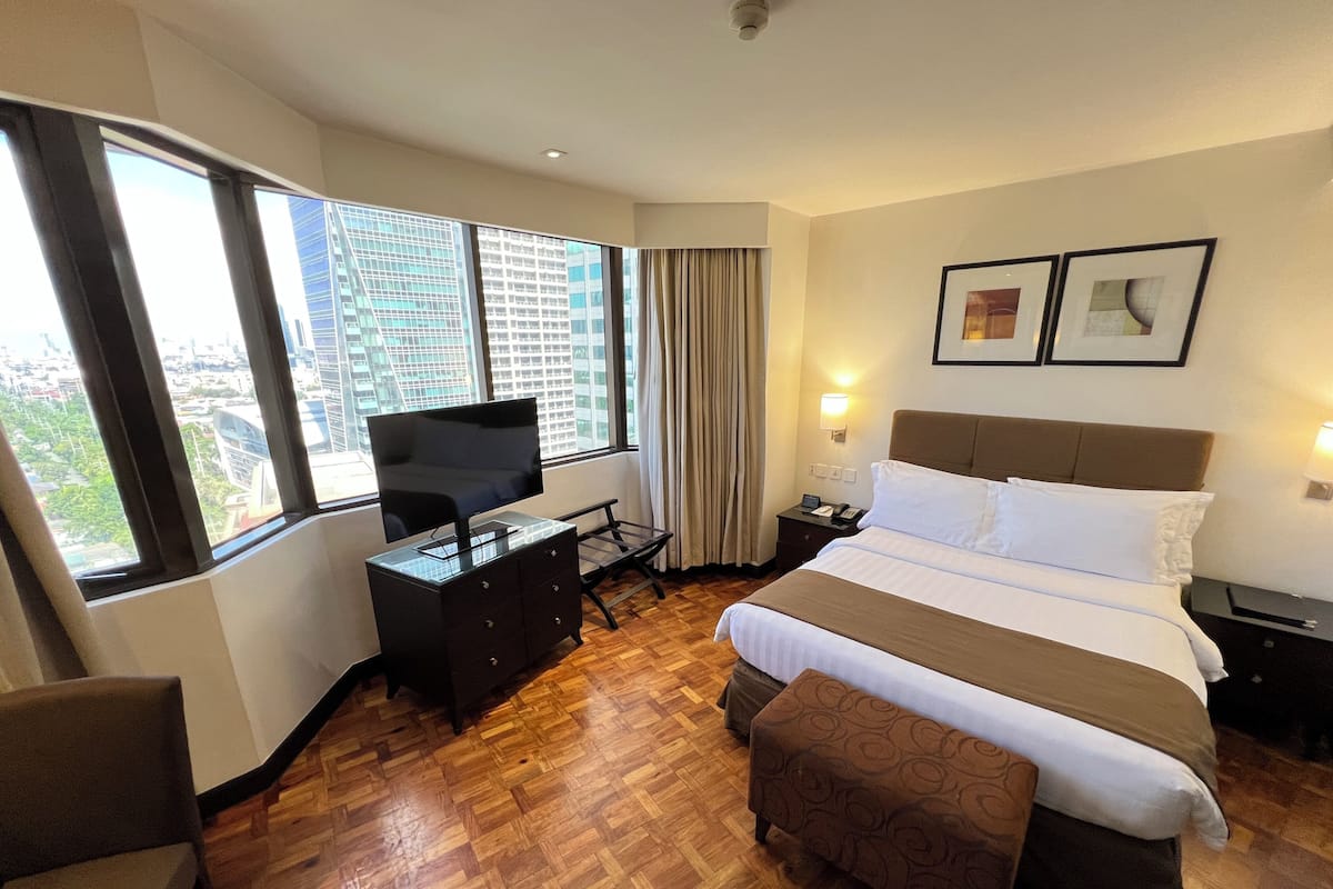 Una habitación de hotel con una cama, un televisor sobre una cómoda, un escritorio y una silla.