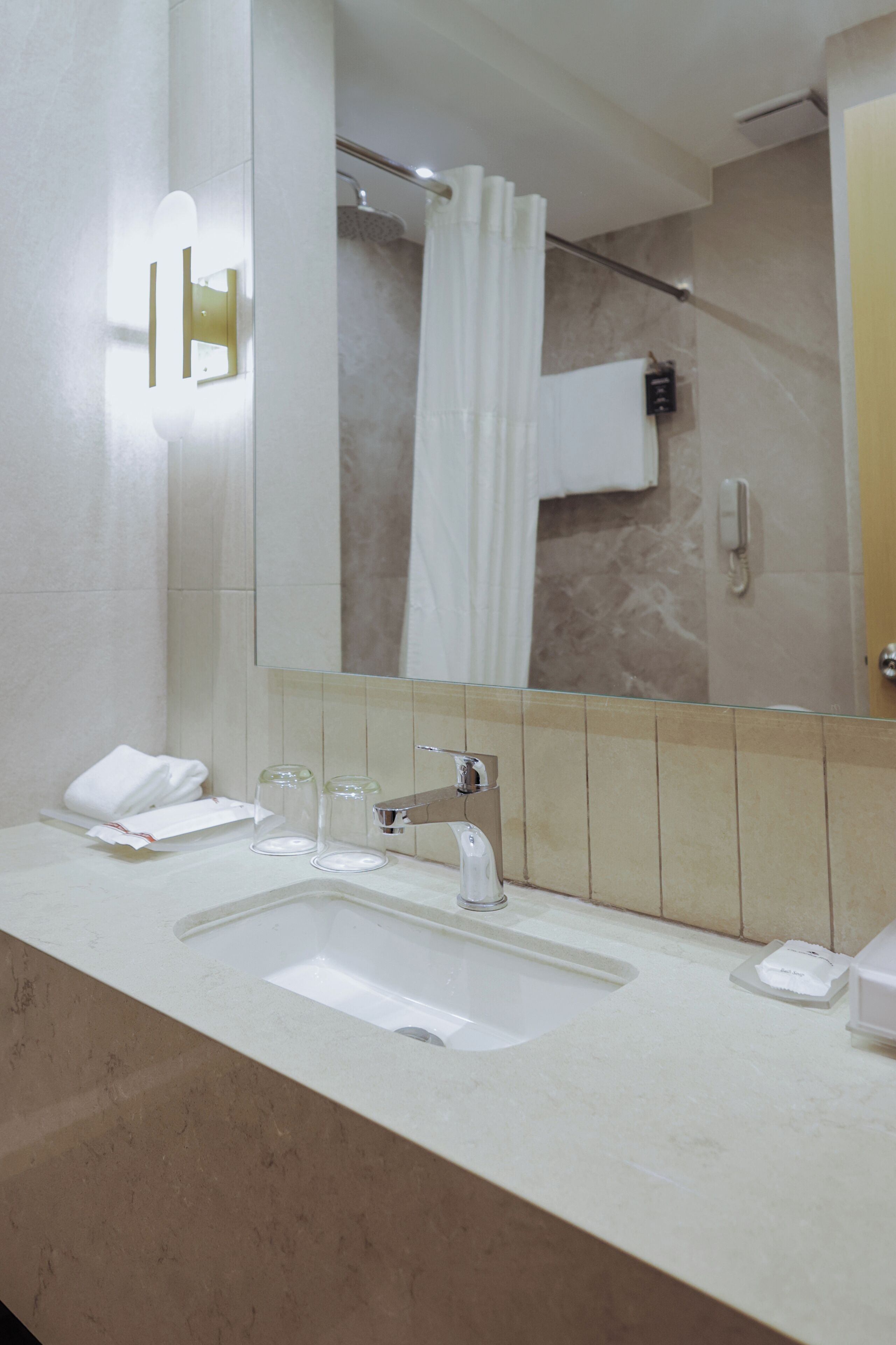 A modern bathroom with a large mirror, a sink, and a shower area.