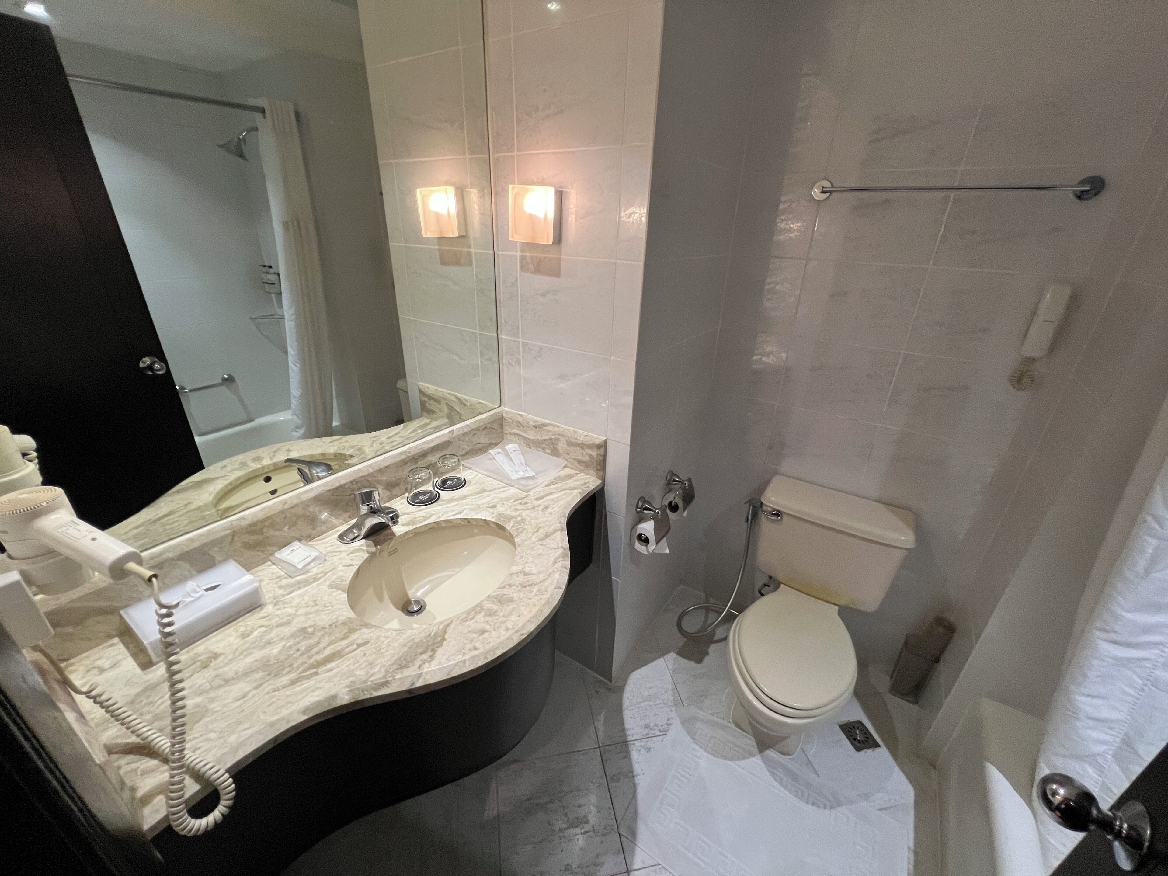 A bathroom with a sink, mirror, toilet, and shower area.