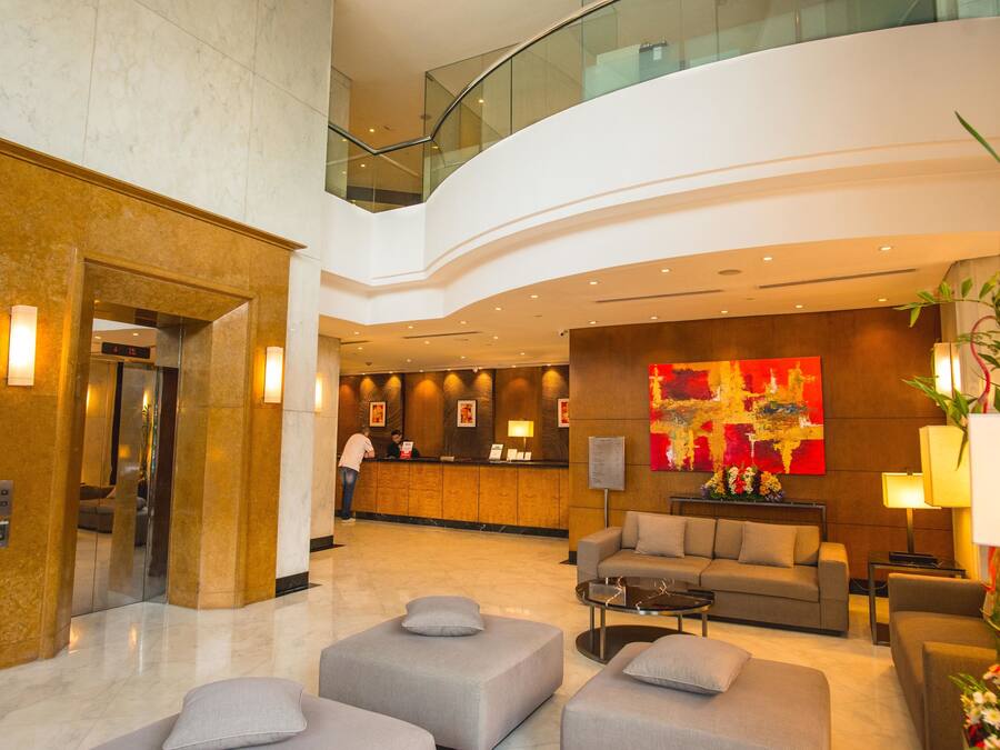 A modern lobby with a reception desk, seating area, and a glass railing overlooking the lower level.