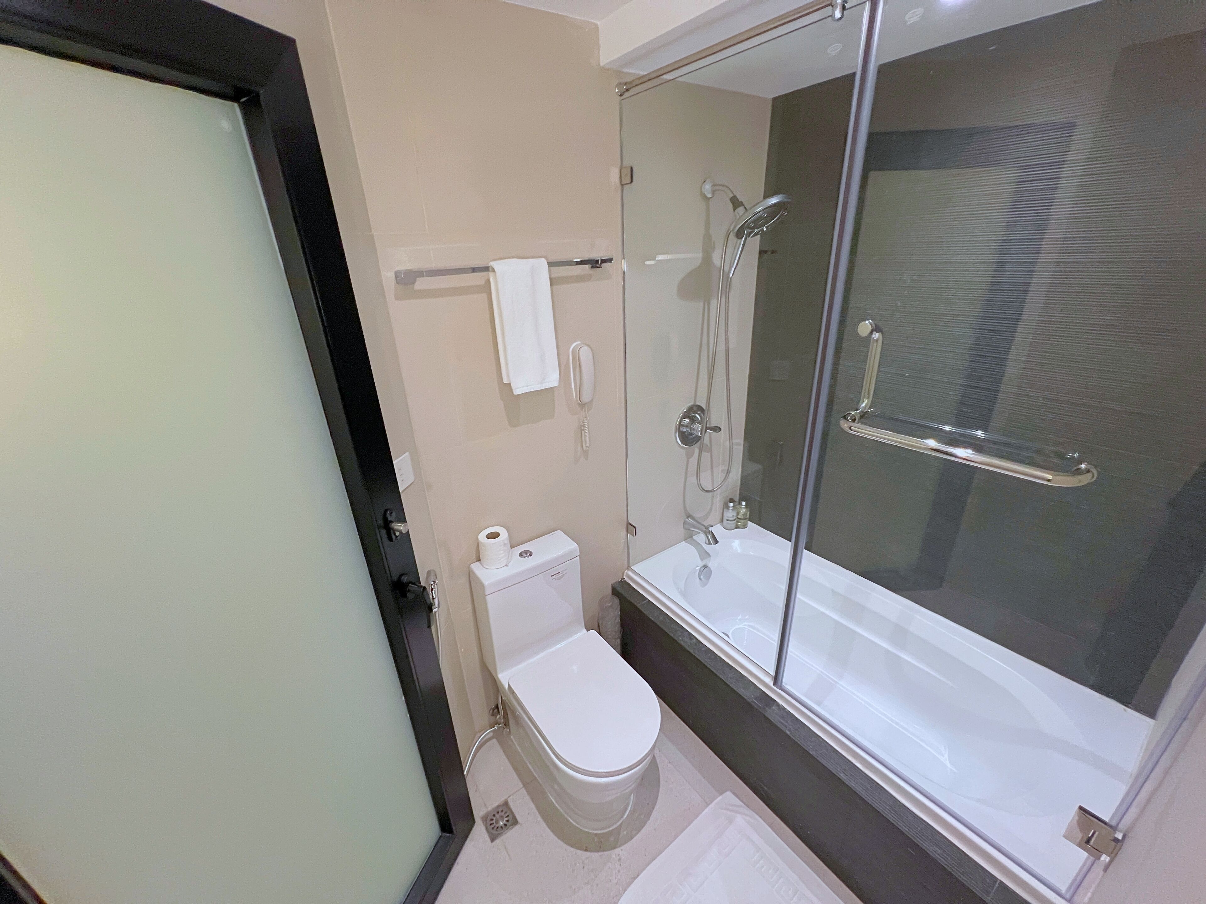 Une salle de bain moderne avec des toilettes, une douche à parois de verre et un lavabo blanc.
