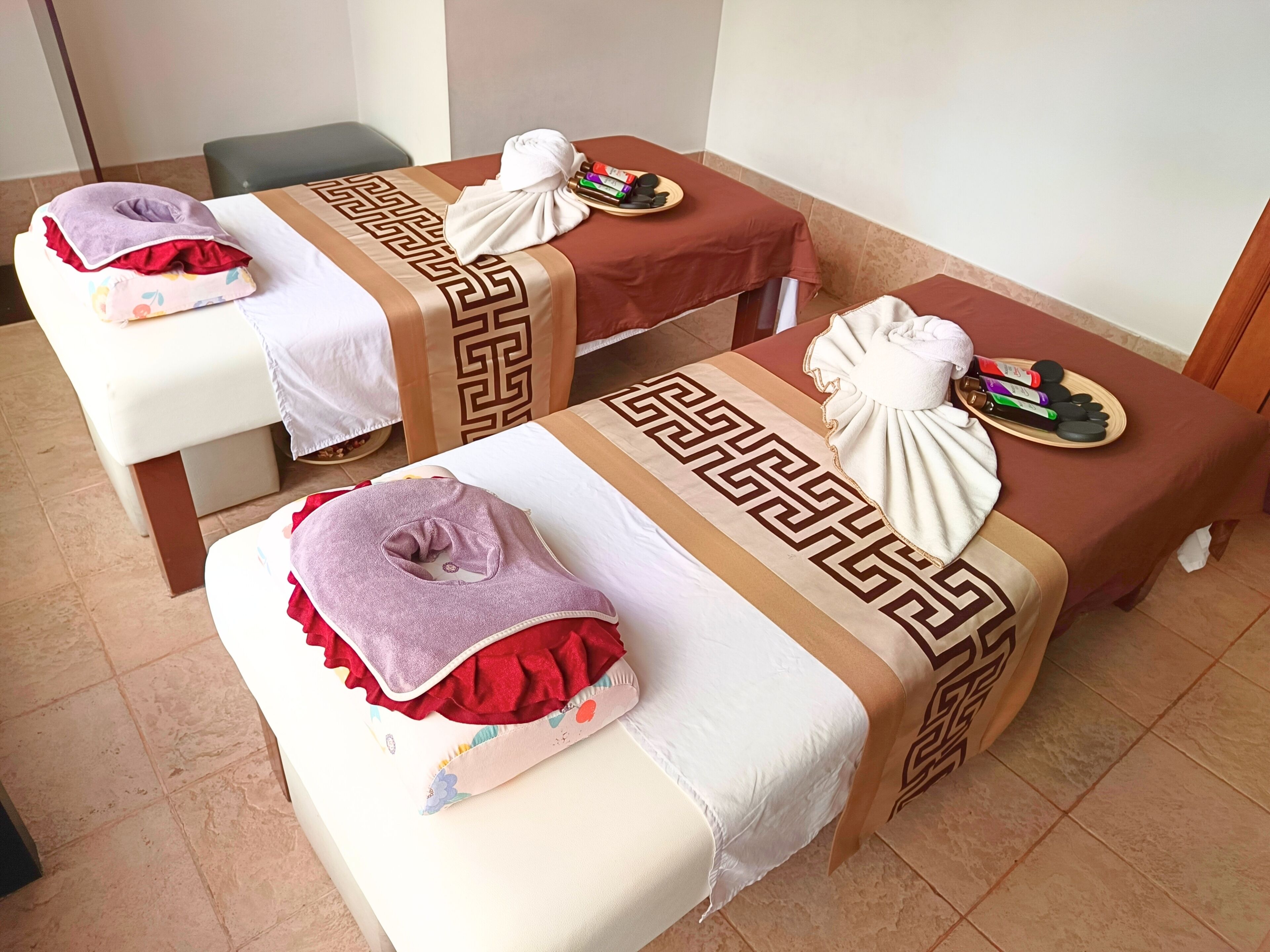 A room with two massage tables, each with towels and massage tools.