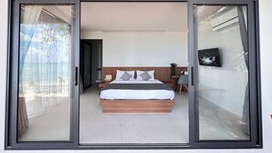 A modern bedroom with a large bed, a nightstand, a chair, and a view through a glass door.