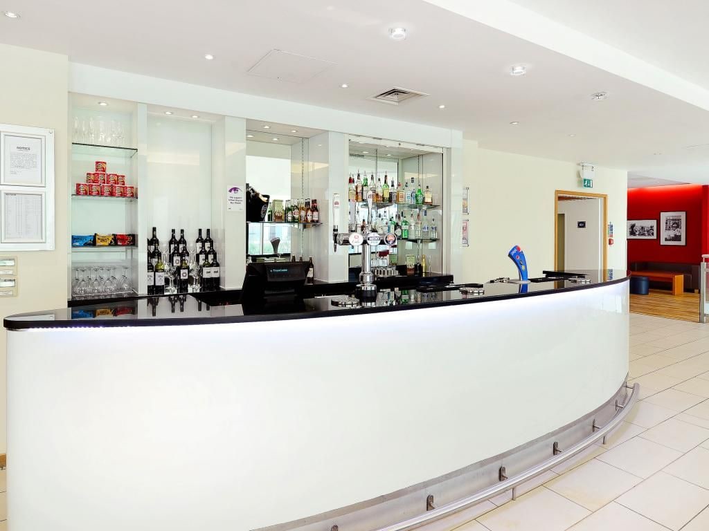 Eine moderne Bar mit einer gebogenen Theke, Regalen mit Flaschen und einer Glasvitrine.