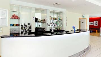 Eine moderne Bar mit einer gebogenen Theke, Regalen mit Flaschen und einer Glasvitrine.