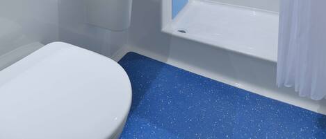 A modern bathroom with a white toilet, a sink, a shower with a glass door, and a blue speckled floor.