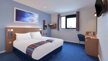 A hotel room with a large bed, a desk, a chair, a TV mounted on the wall, and a window with curtains.