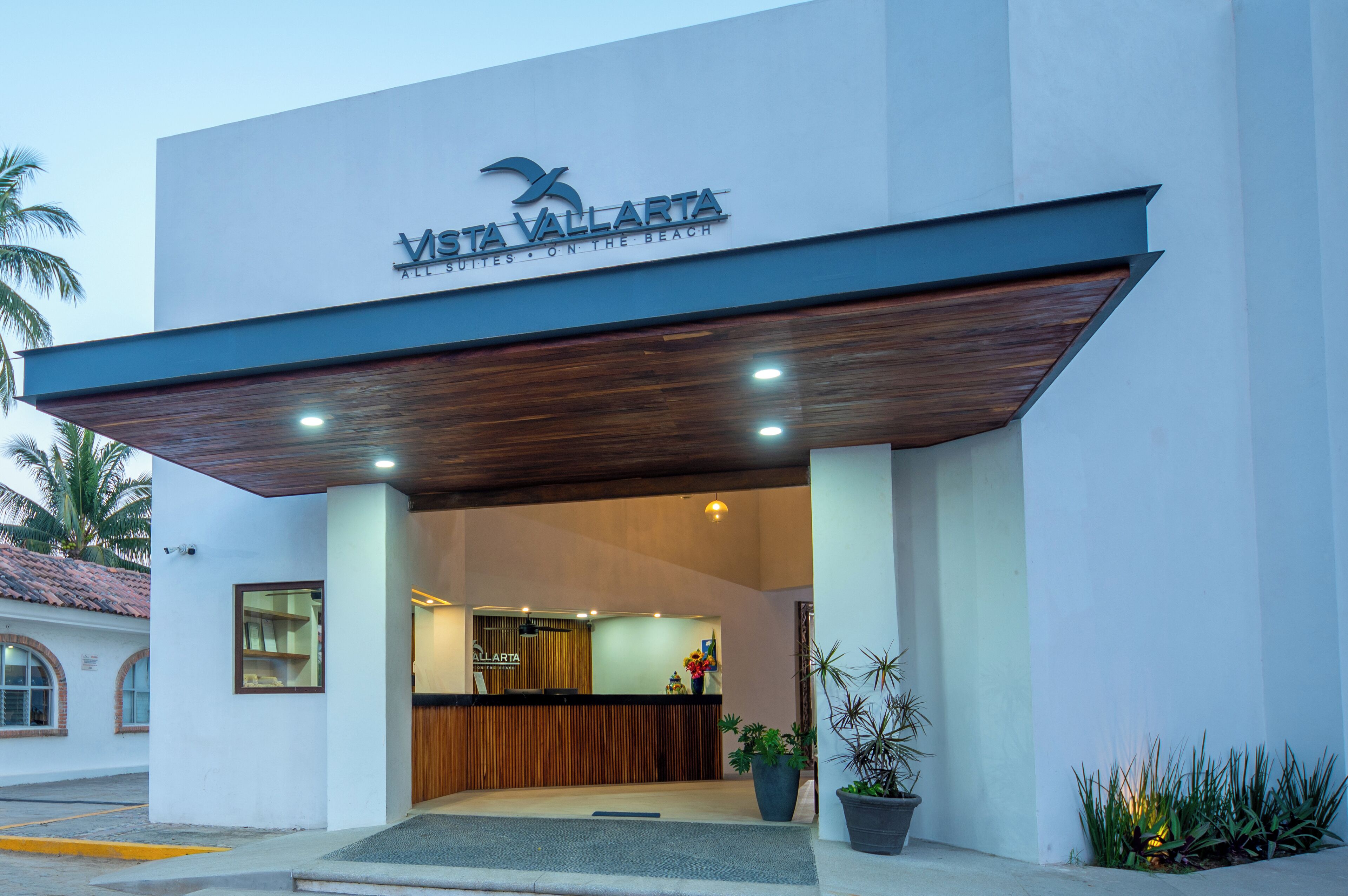 The exterior of Vista Vallarta, featuring a modern design with a wooden overhang and a reception area visible inside.