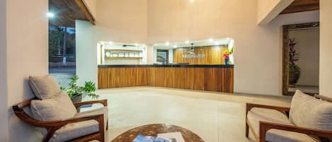 A reception area with a wooden reception desk, two upholstered chairs, and a coffee table with brochures.